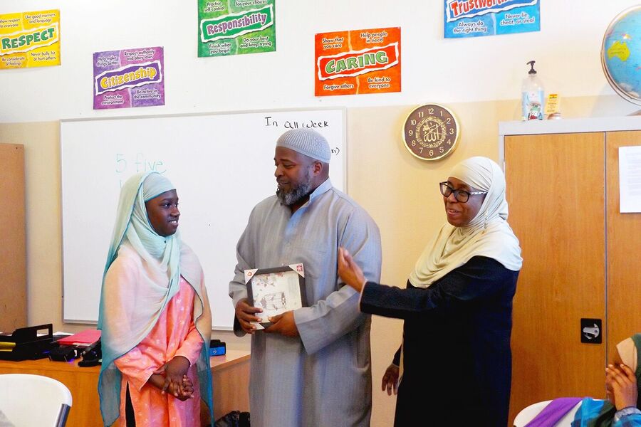 Nisaa’s Academy teachers and students in a classroom with character-value posters on the wall.