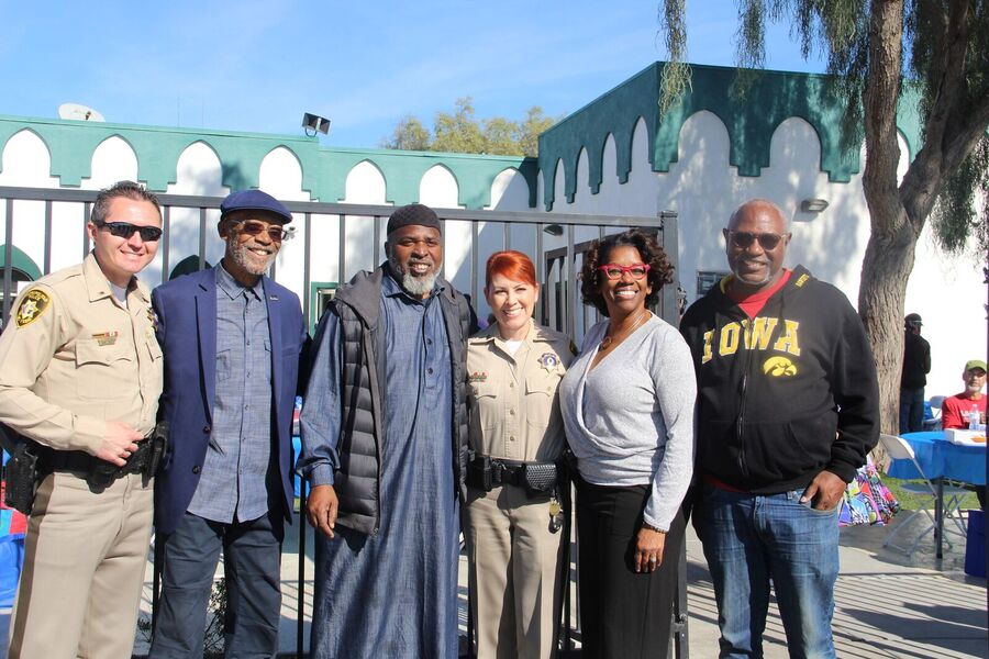 Police officers and community leaders standing together outside Masjid As-Sabur.